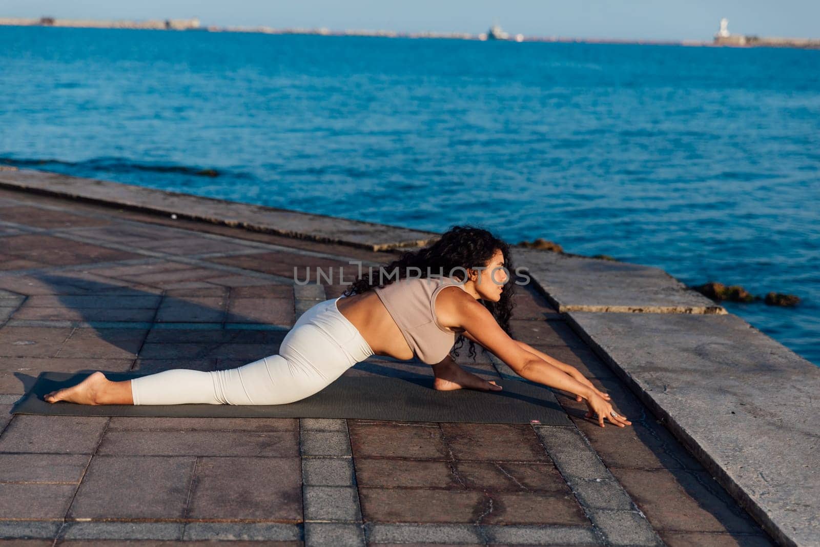 Woman doing yoga asana breathing practice on the beach by the sea by Simakov