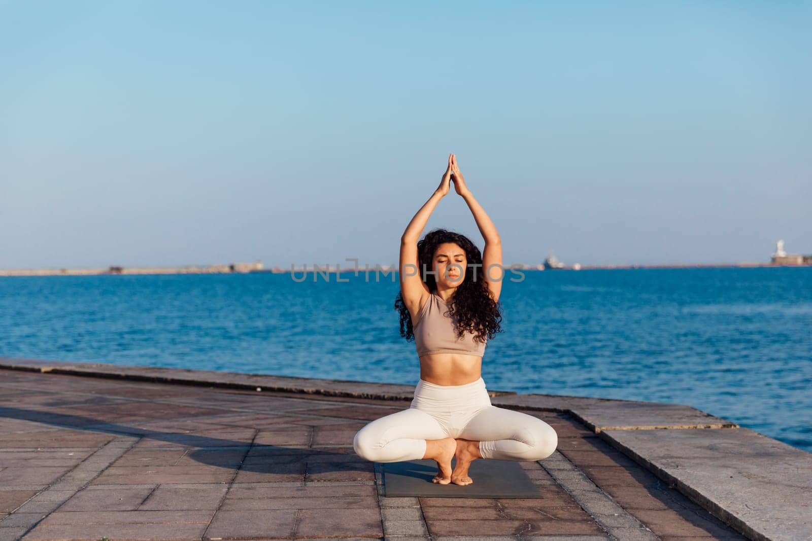 Woman doing yoga asana practice on the beach by Simakov