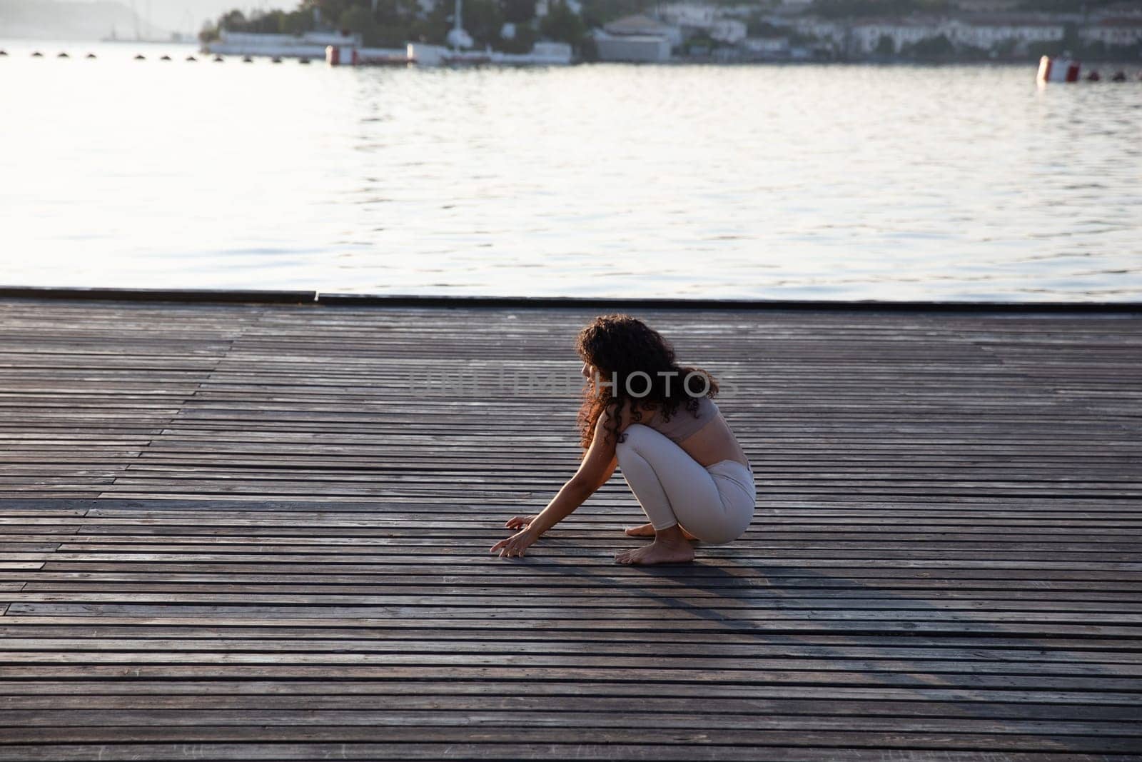 Woman doing yoga asana practice on the beach by Simakov