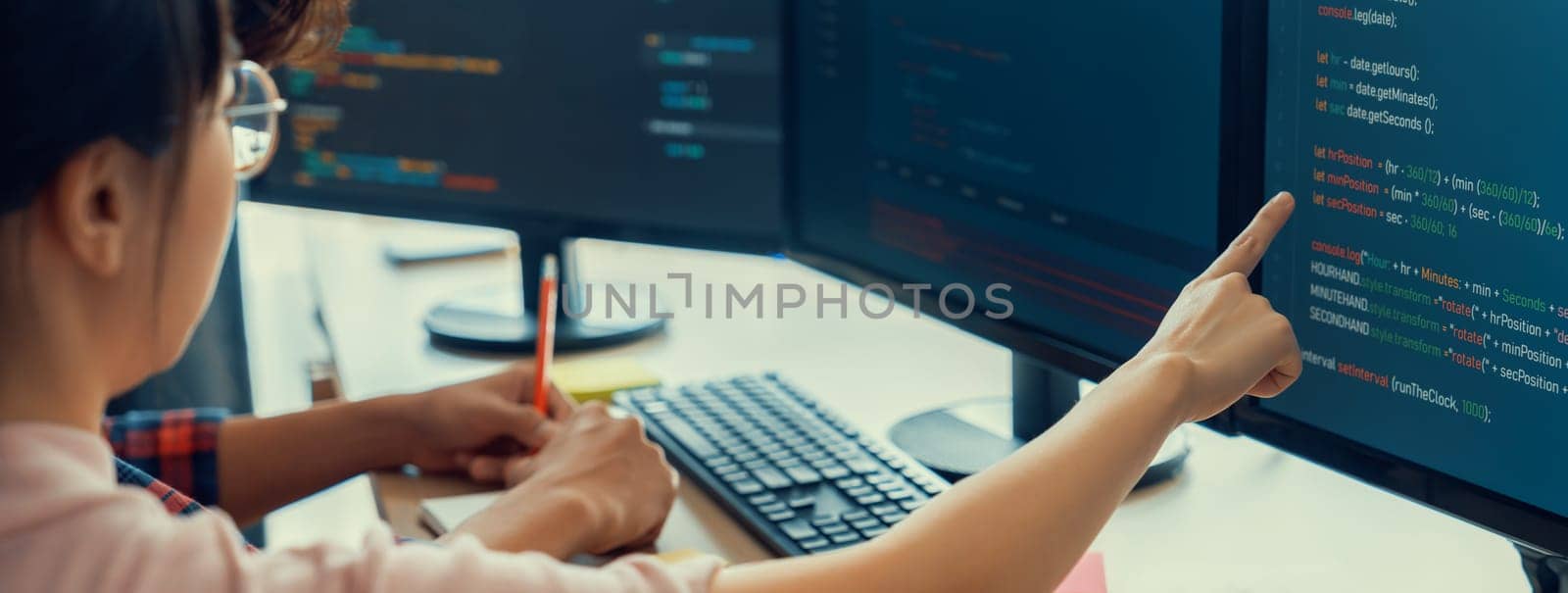 Female programer taking a note while young skilled web developer present program while computer displayed program code at modern office company. Java script, web design concept. Burgeoning.