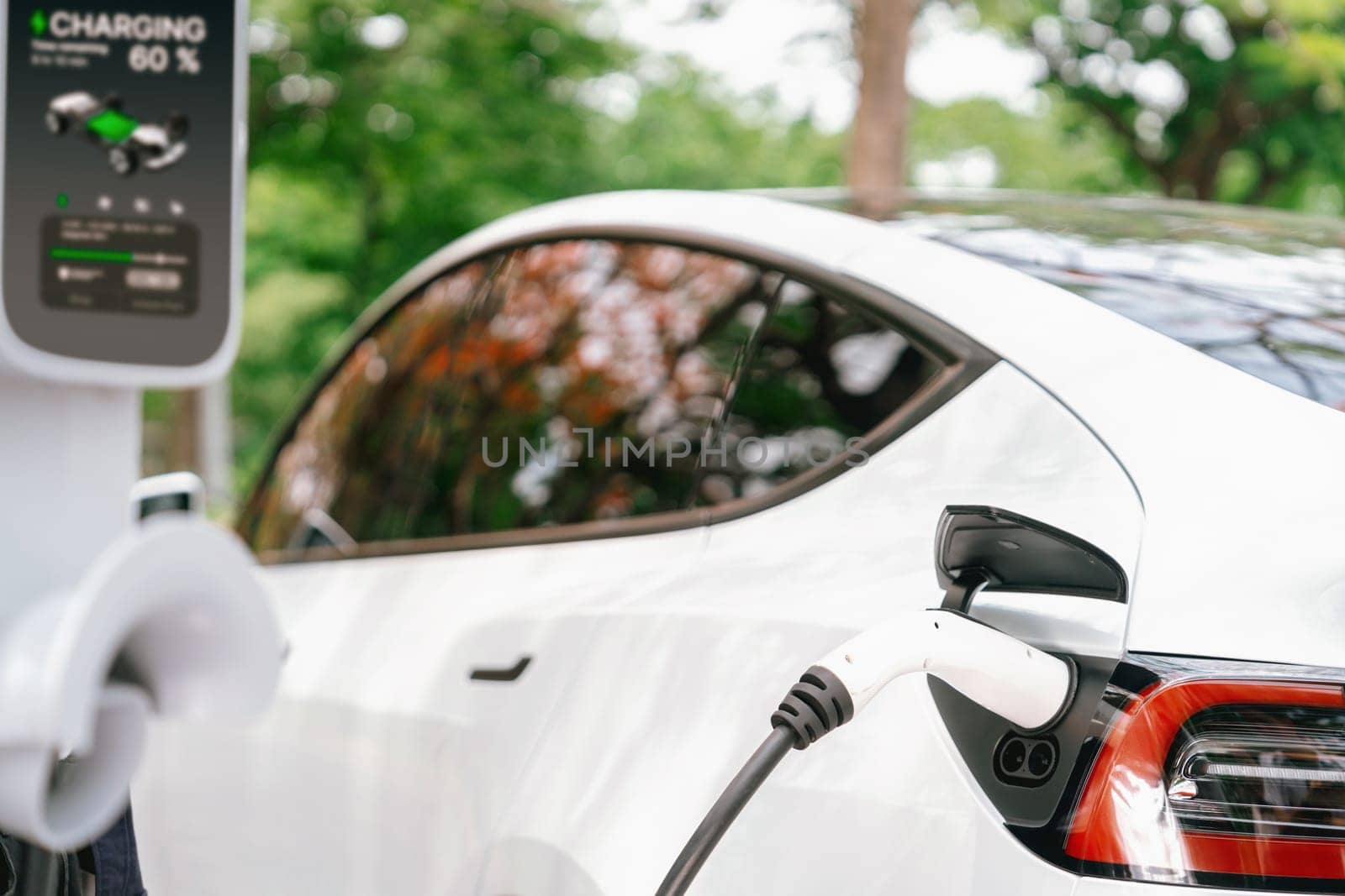 Man recharging battery for electric car in autumn. Exalt by biancoblue