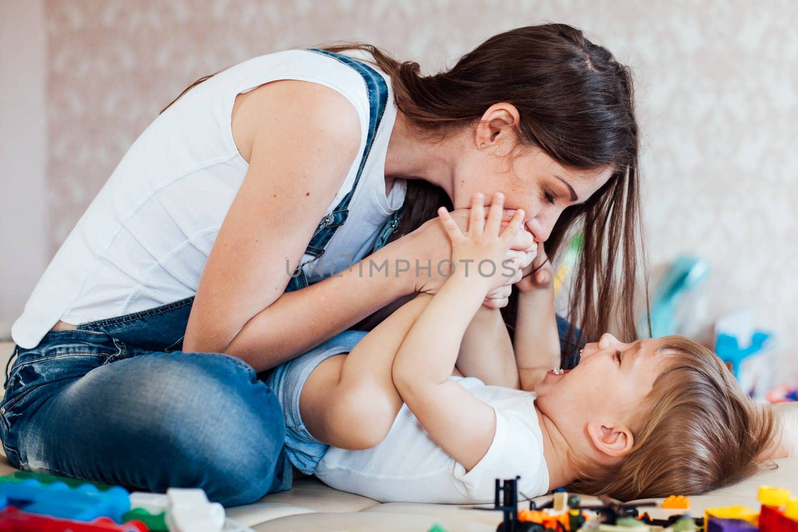 mom plays with a little boy with love kisses laughs by Simakov