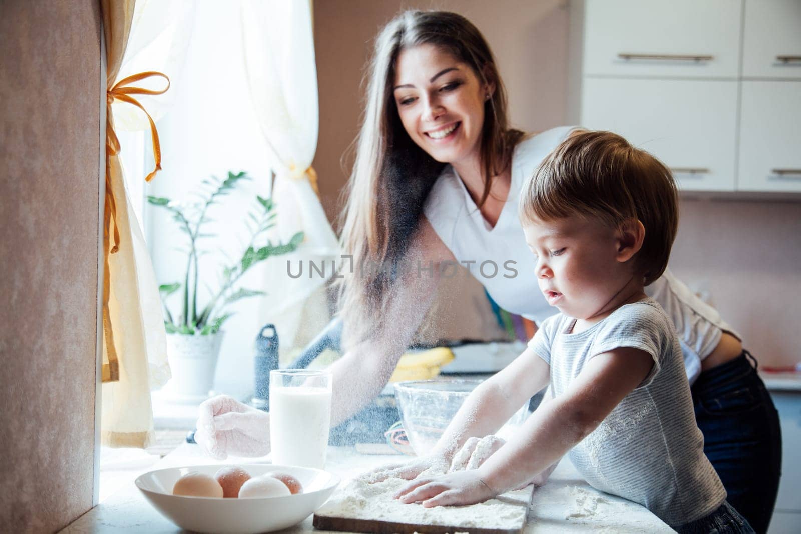 mother and young son prepare a cake in the kitchen by Simakov