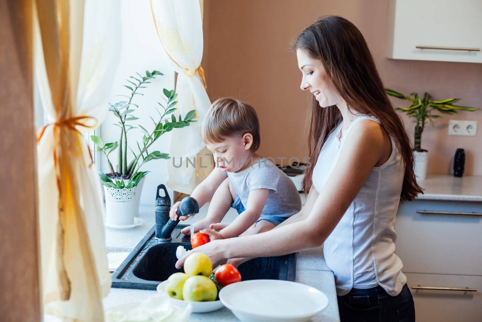 kitchen mom son wash fruits and vegetables by Simakov