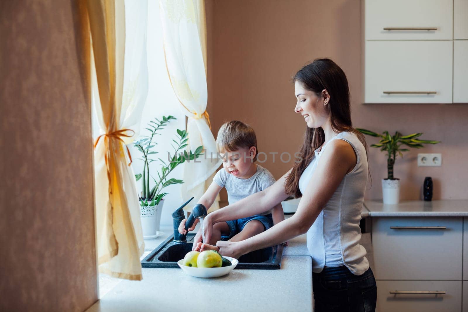 kitchen mom son wash fruits and vegetables by Simakov
