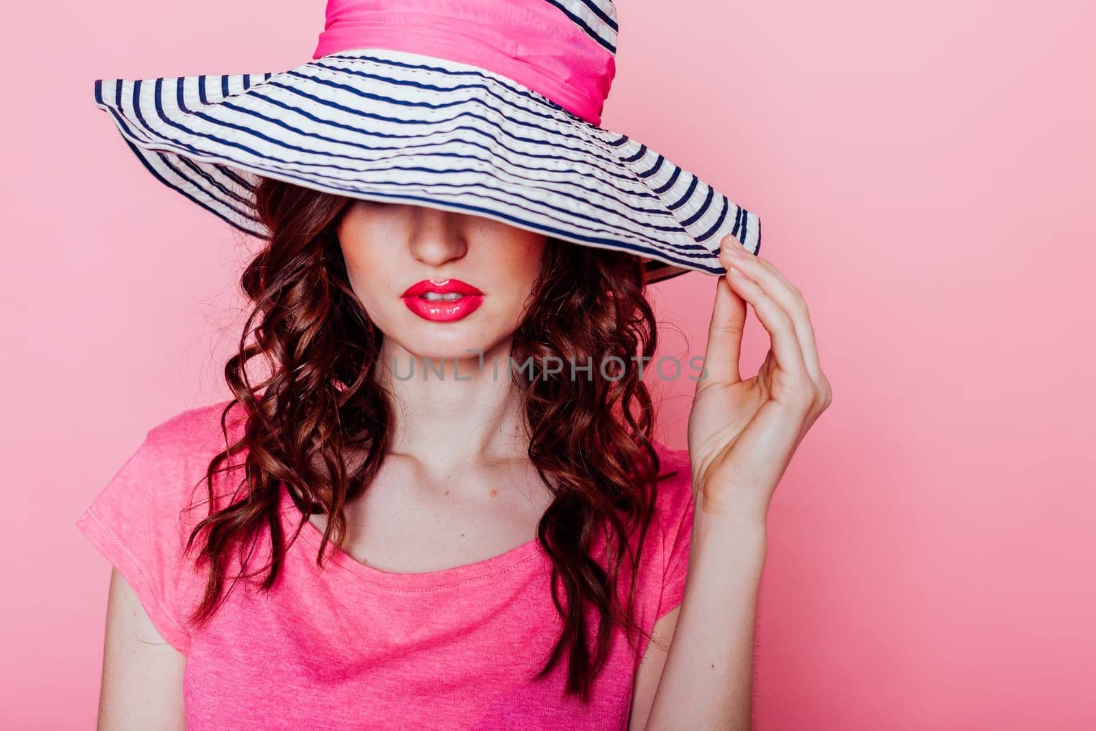 girl pinup-style in a pink dress with hat with brim