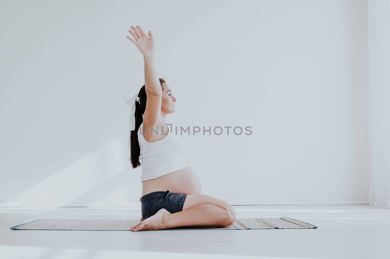 a pregnant woman is engaged in gymnastics and yoga by Simakov