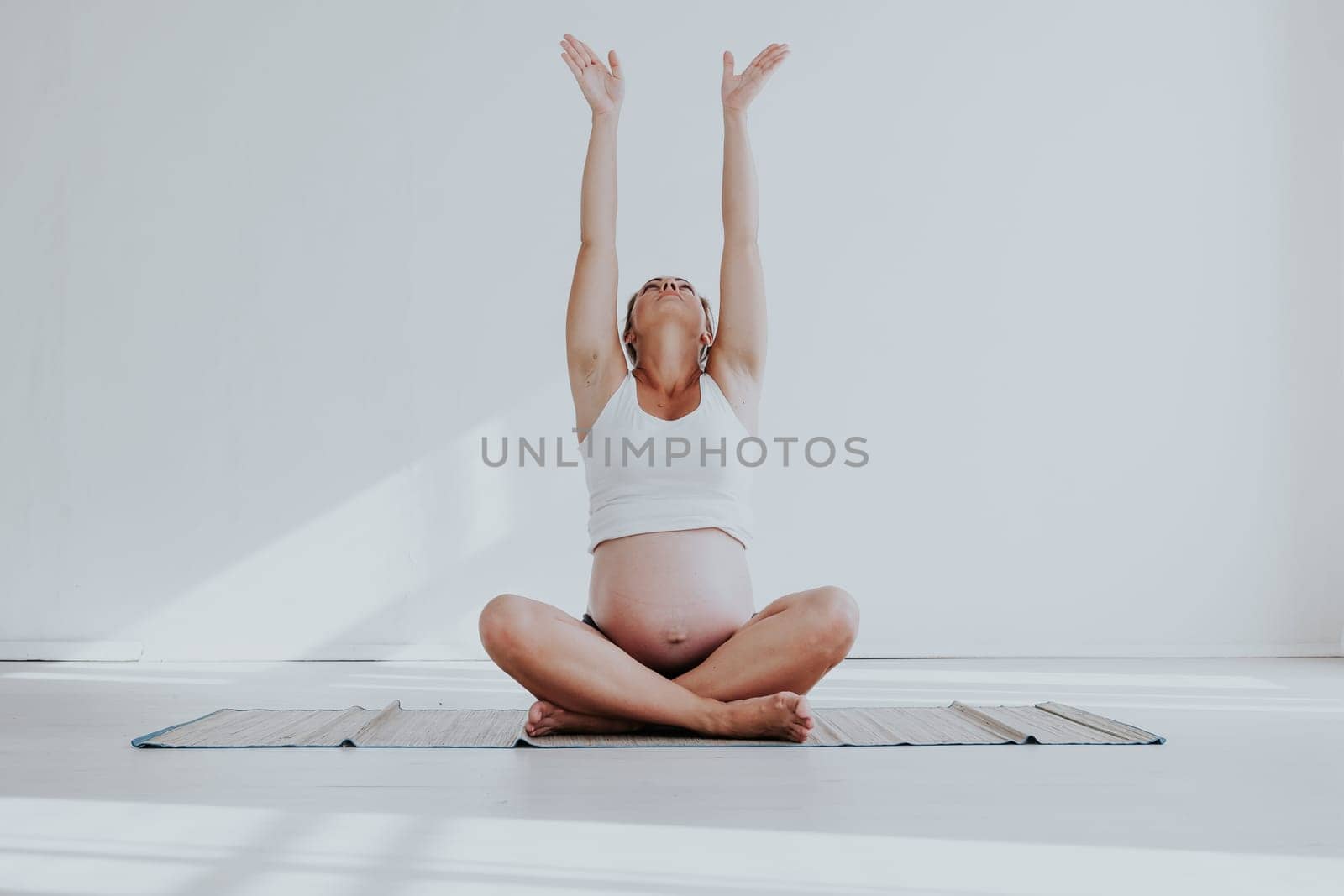 a pregnant woman is engaged in gymnastics and yoga by Simakov