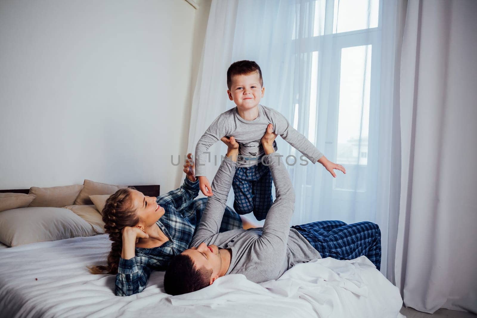 mom dad son in the morning in bed by Simakov