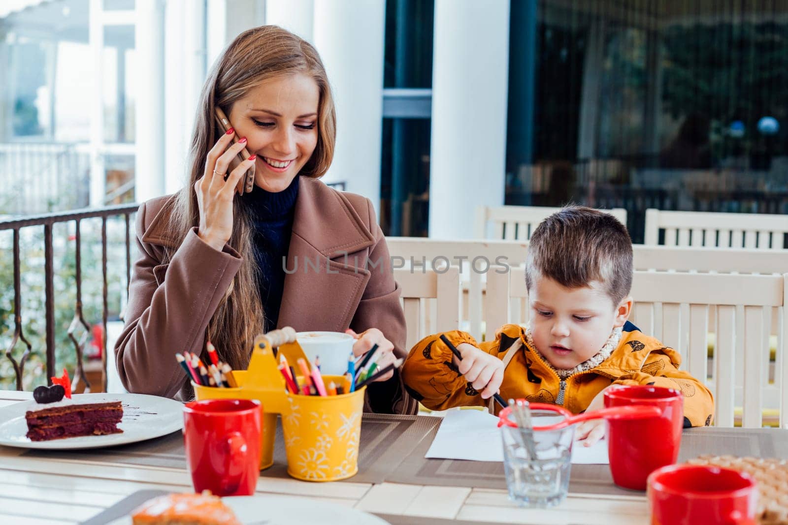 Restaurant mom with son talking on the phone by Simakov