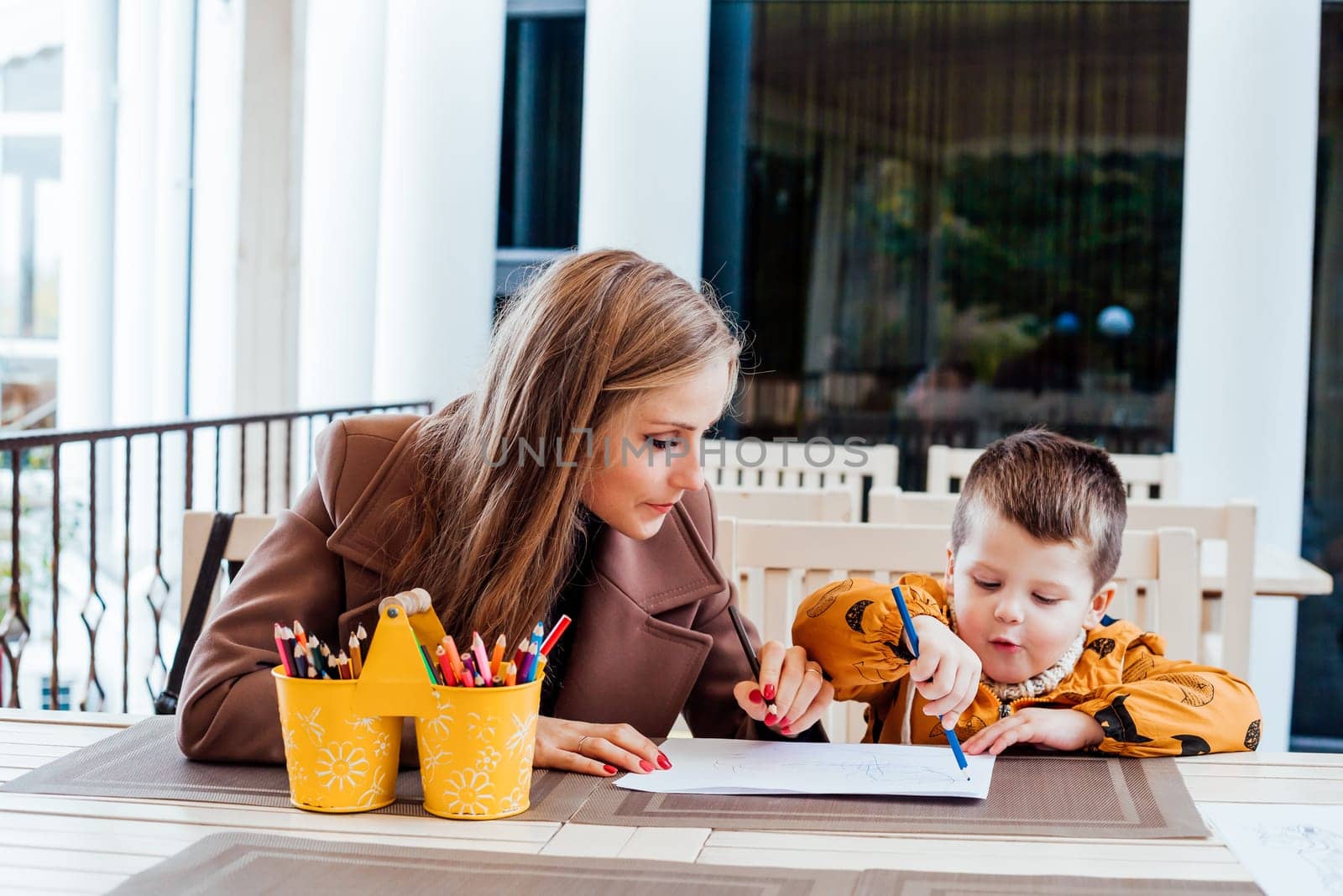 woman teaches the boy to draw with colored pencils 1