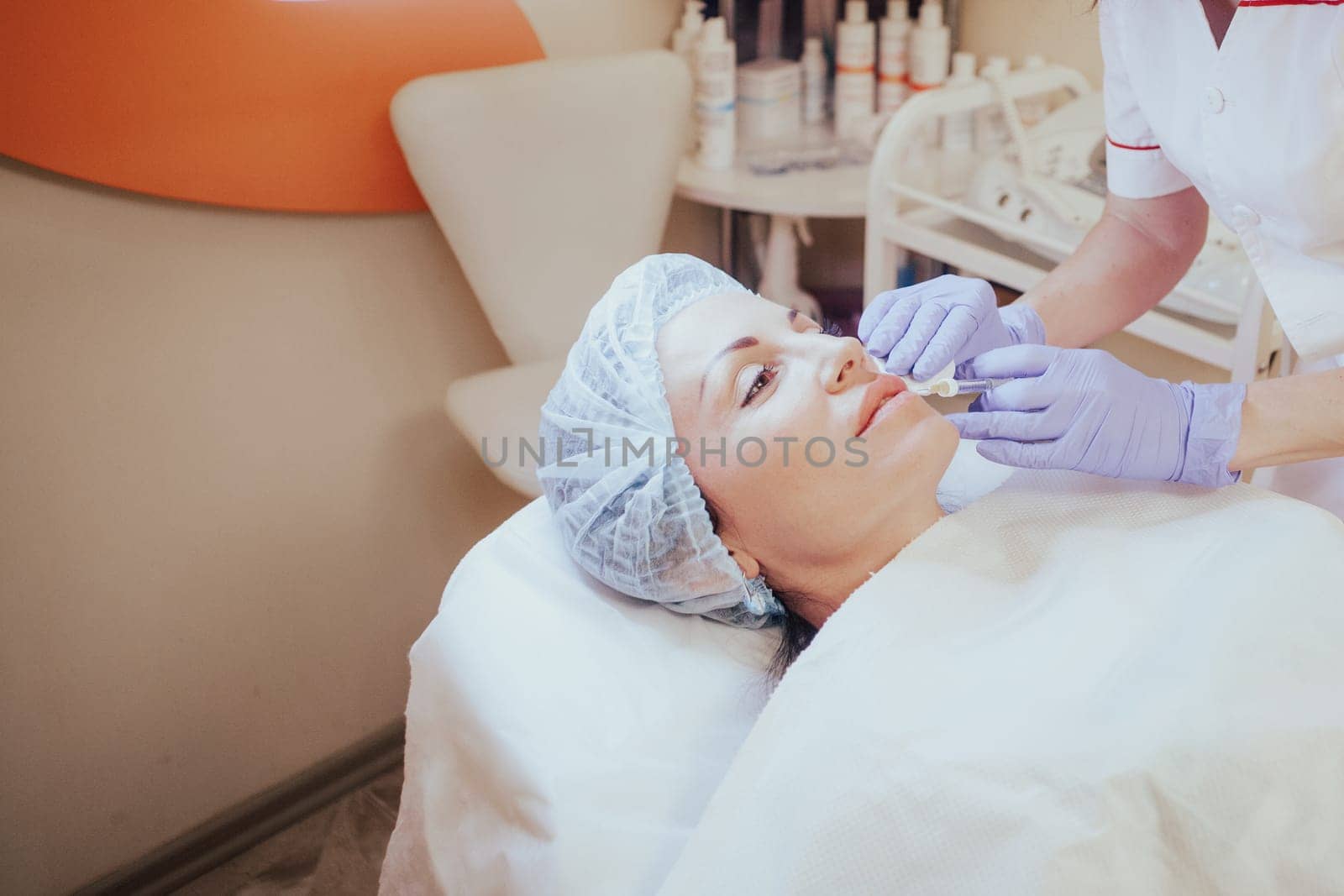 Cosmetology doctor makes injection in the lips of the woman