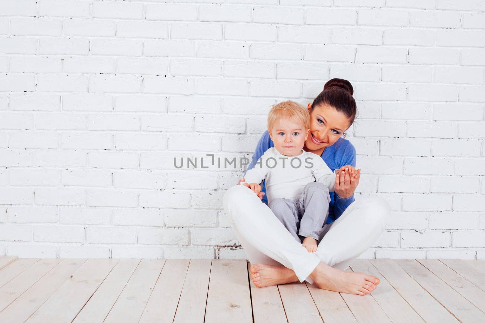 mom and young boy sitting on the floor near the brick wall