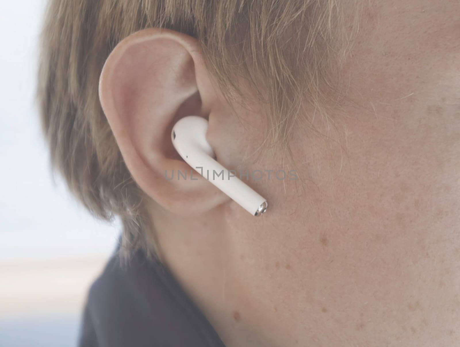 Man wearing wireless white headphones. Stock. Close-up of man wearing small Bluetooth headphones. Modern comfortable headphones with excellent sound.