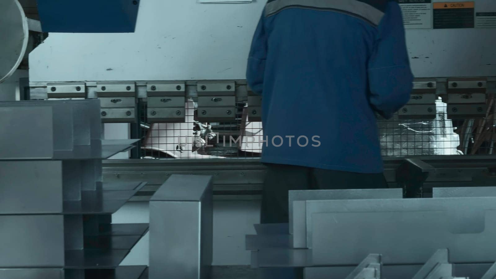 Worker manually assembles machine with metal parts. Creative. Work at factory for collection of metal structures and machine tools. Worker collects lot of metal parts at factory.