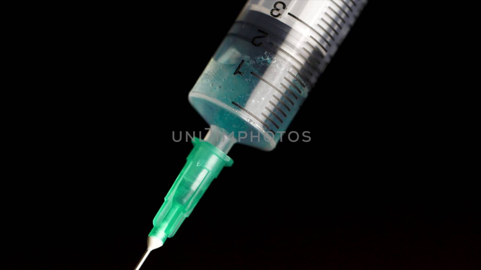 Taking vaccine into a glass syringe from a ampule on a black background. Closeup. Syringe is typed in turquoise fluid injection from illness serious illnesses, the concept of medicine.