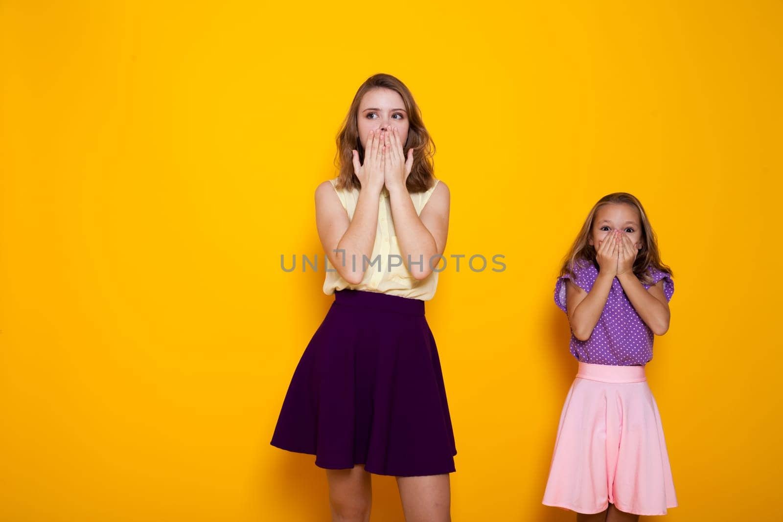 Two fashionable sisters cover their mouths with their hands by Simakov