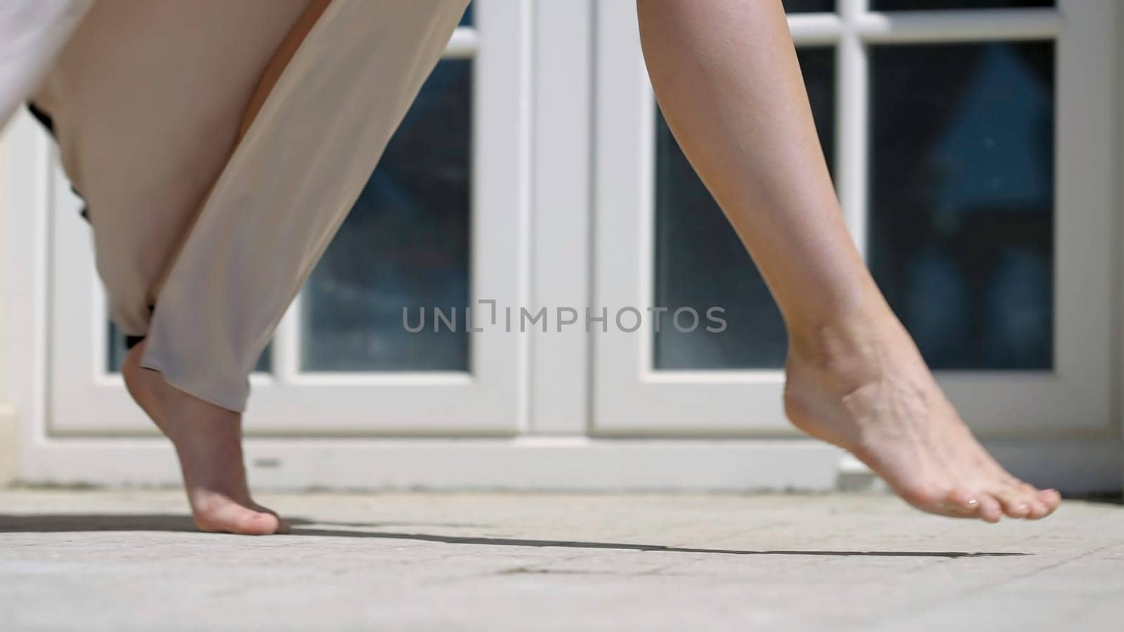 Beautiful legs of attractive woman in dress. Action. Woman walks beautifully barefoot in dress on sunny day. Beautiful gentle gait of woman in dress.
