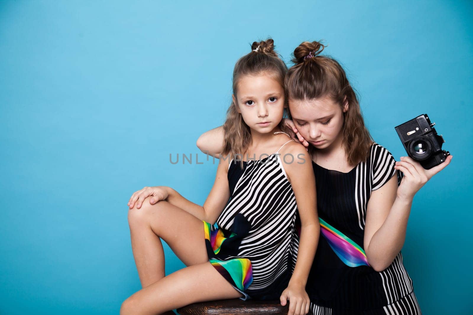 Two fashionable girls with a camera on a blue background