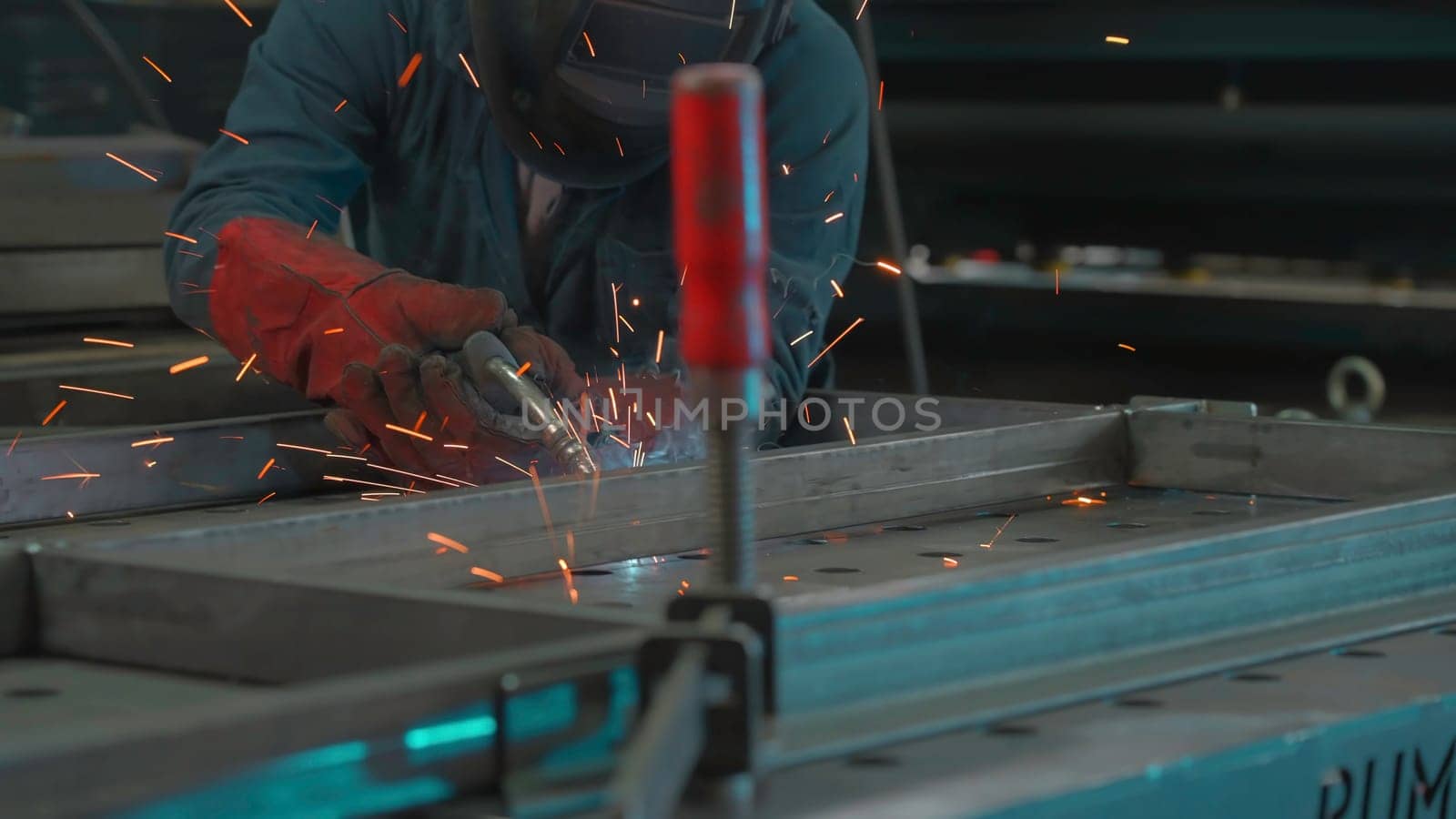 Man in mask works with welding metal structures at factory. Creative. Welder in equipment works at industrial plant. Worker with welding and welding sparks from metal.