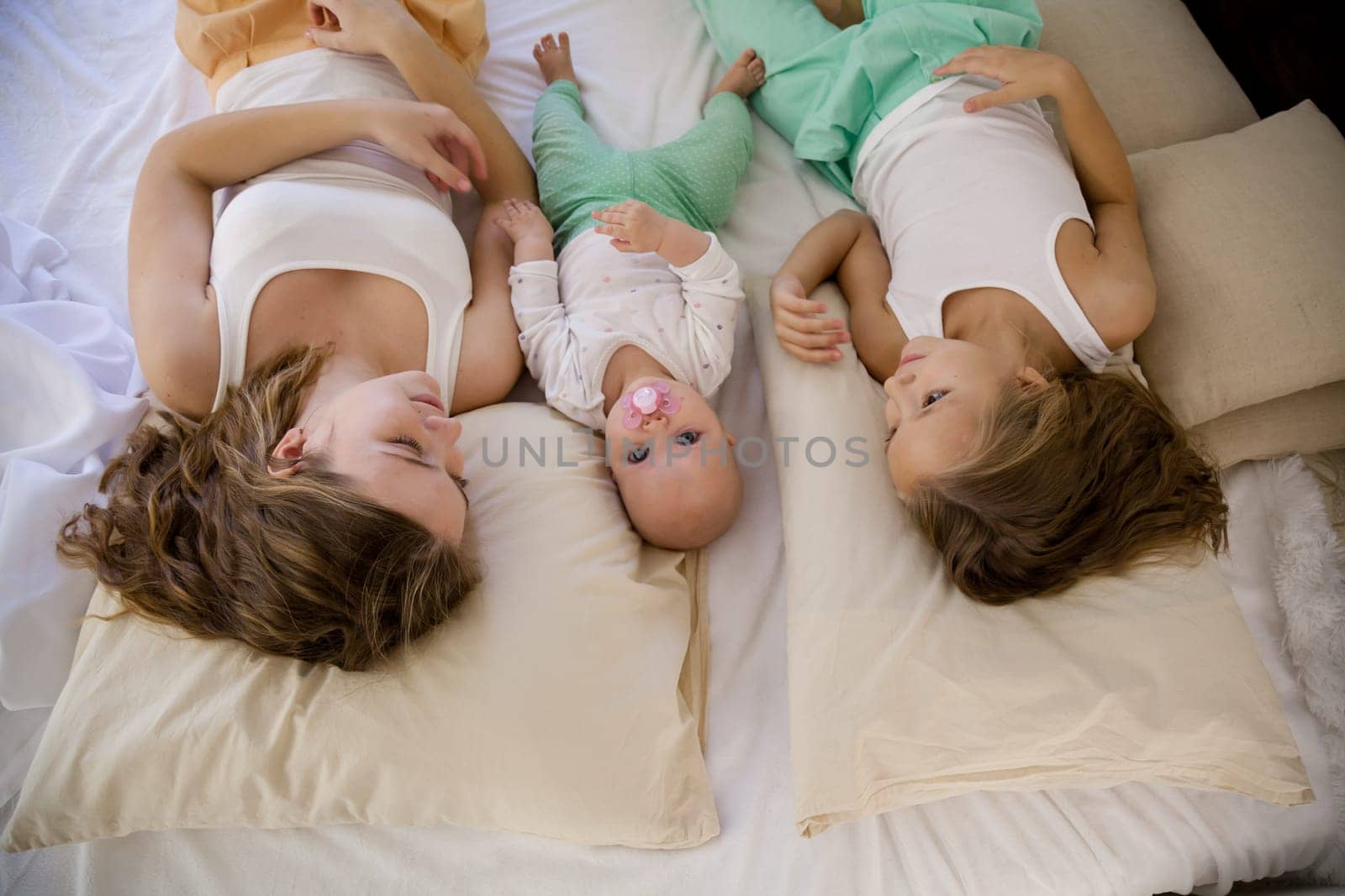 three sisters on the bed in the bedroom in the morning by Simakov