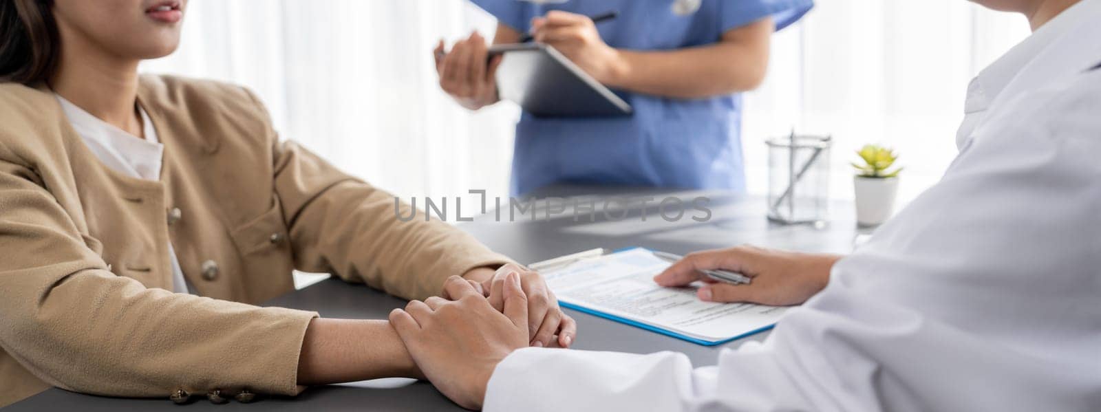 Doctor show medical diagnosis report and providing compassionate healthcare consultation while holding young patient hand for being supportive and professional in doctor clinic office. Neoteric