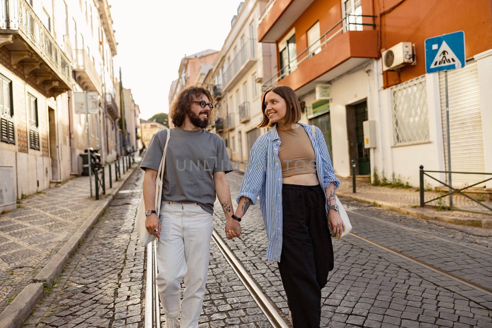 Smiling couple in love holding hands while walking on old city street. High quality photo