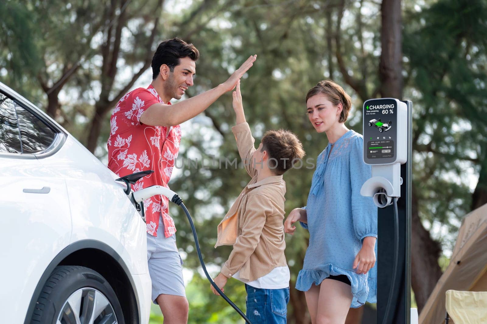 Lovely family recharge EV car with EV charging station in campsite. Perpetual by biancoblue