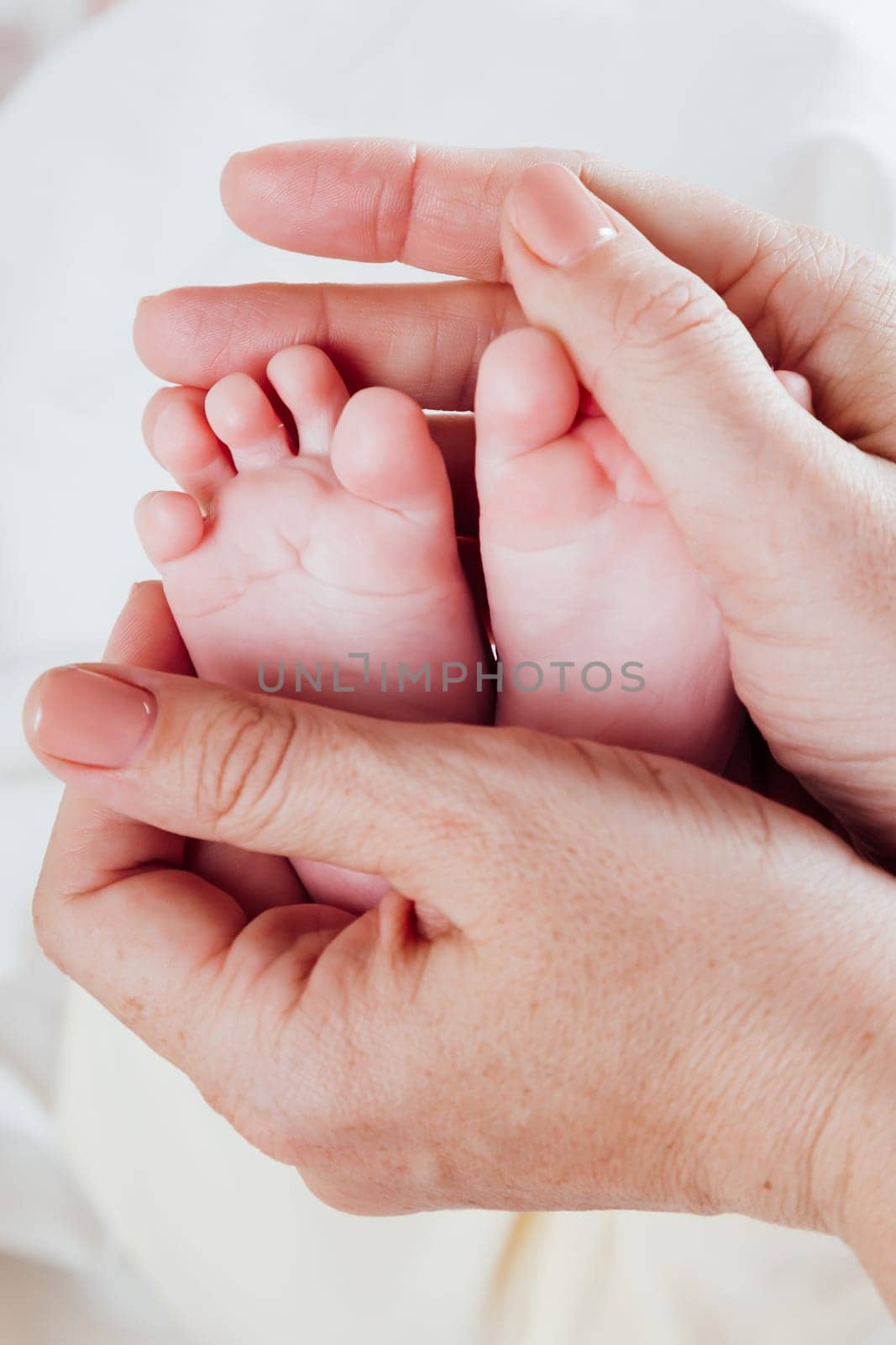 mom's hands hold the feet toes baby