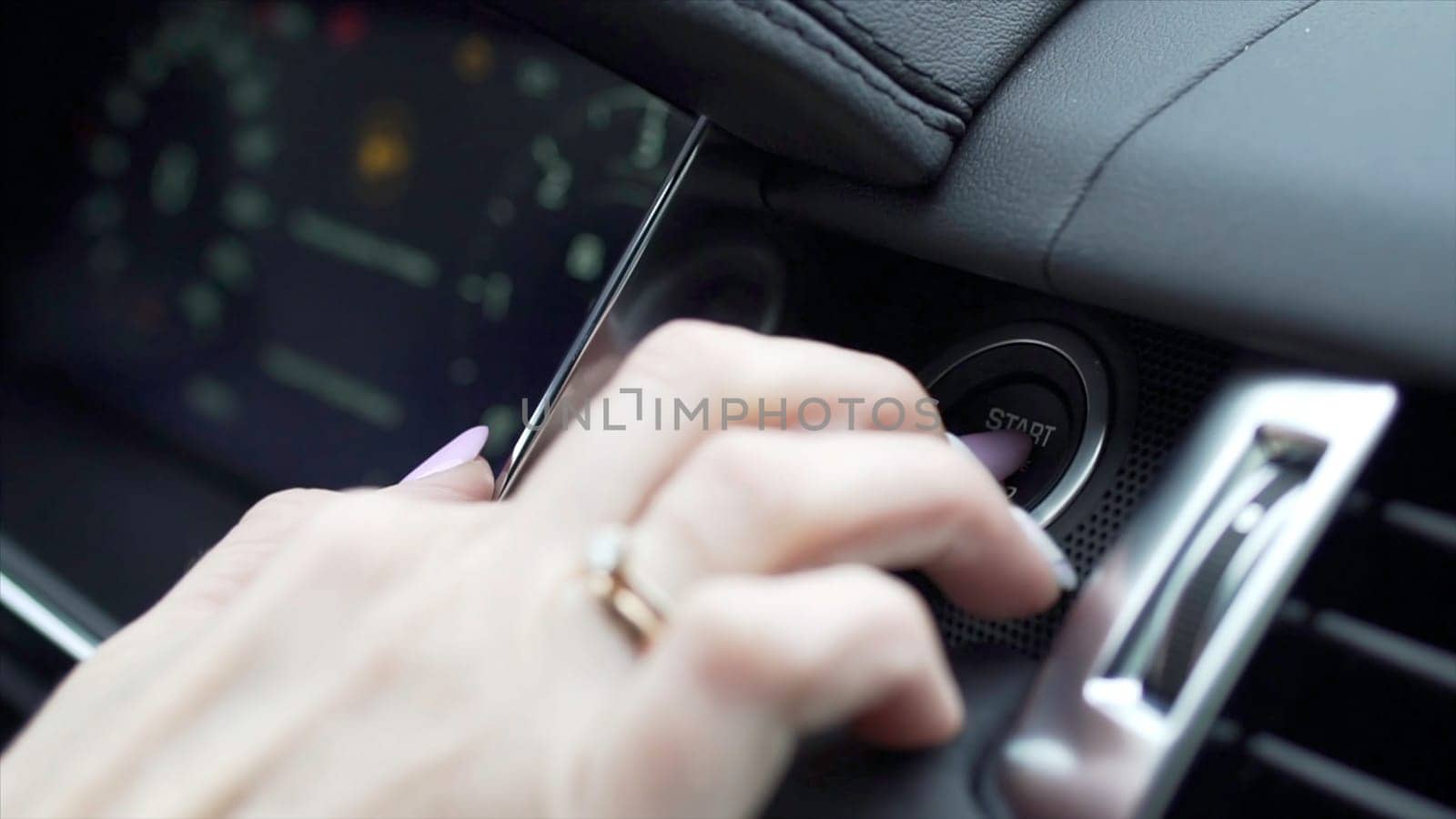 Finger pressing the Engine start stop button of a car. Stock. Car driver starting the engine.