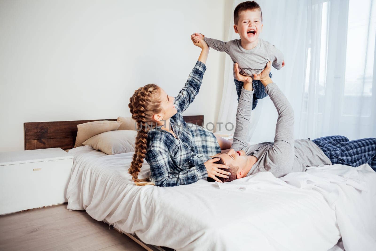 mom dad and son lie on the bed at home woke up