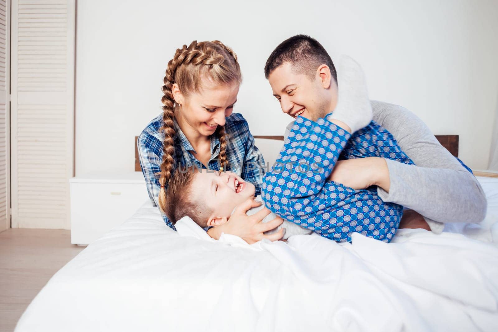 mom dad and son lie on the bed at home dream by Simakov