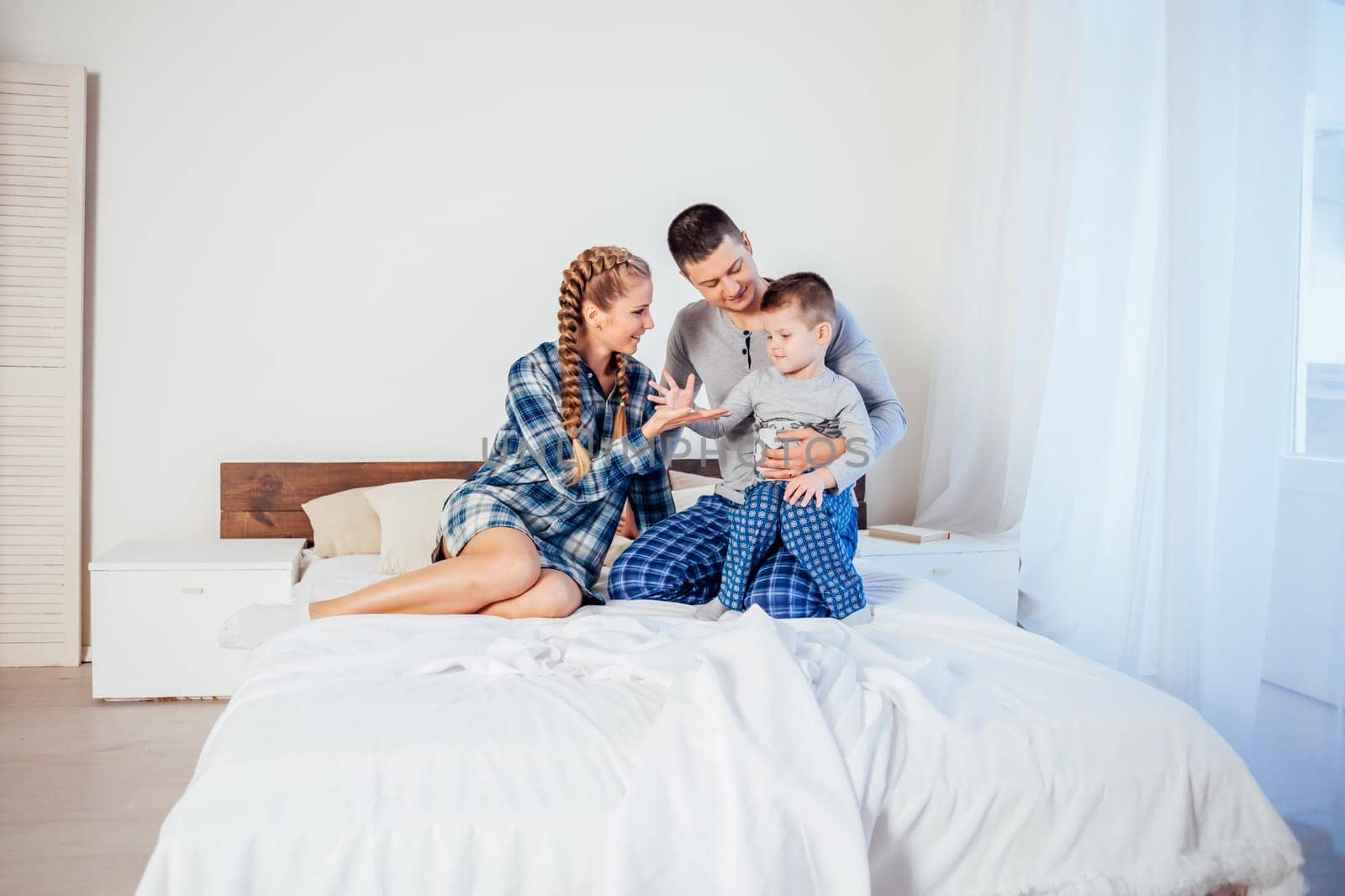 mom dad and son in the morning lying on the bed at home 1