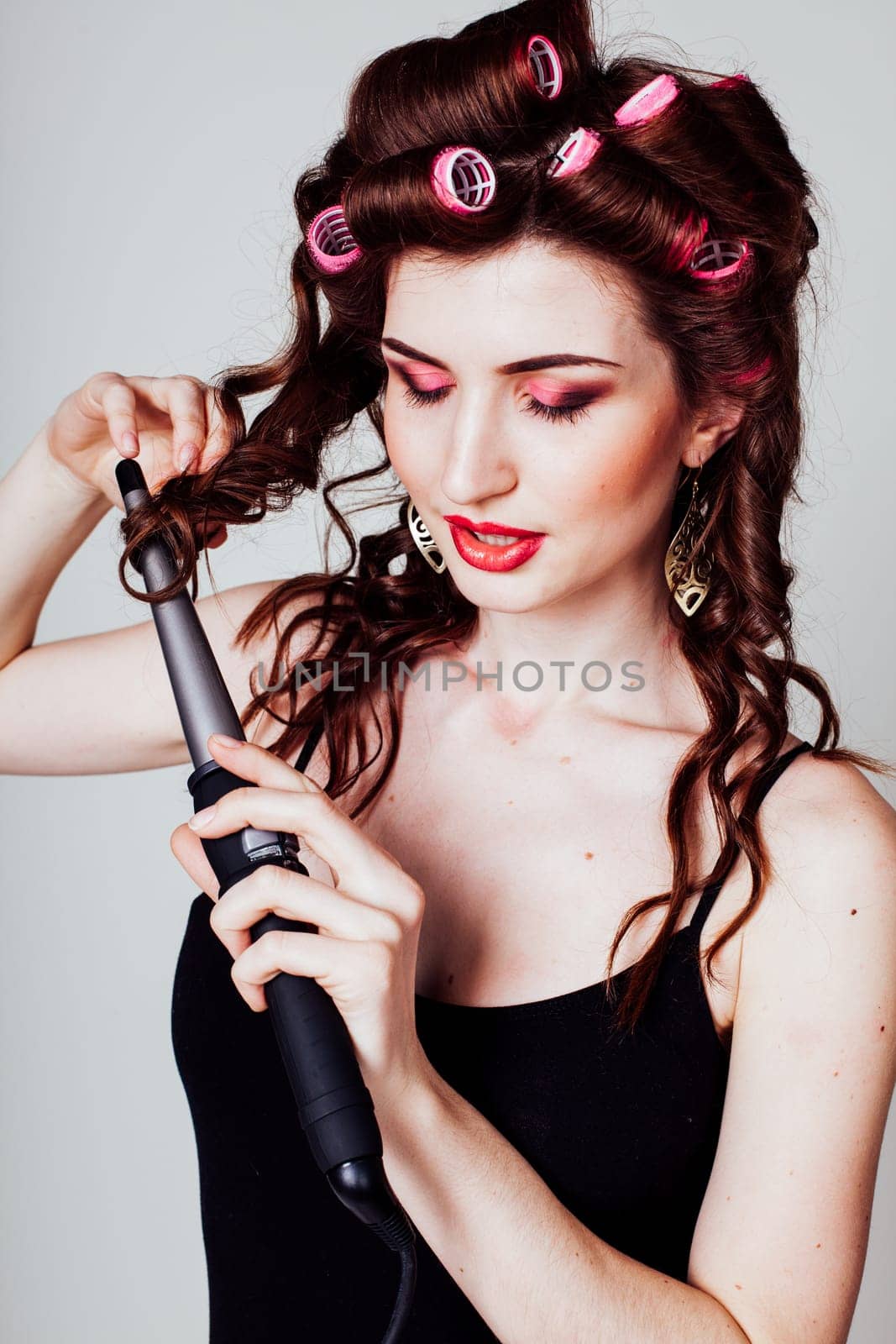 the girl with the curling Tong curler makes hairstyle by Simakov