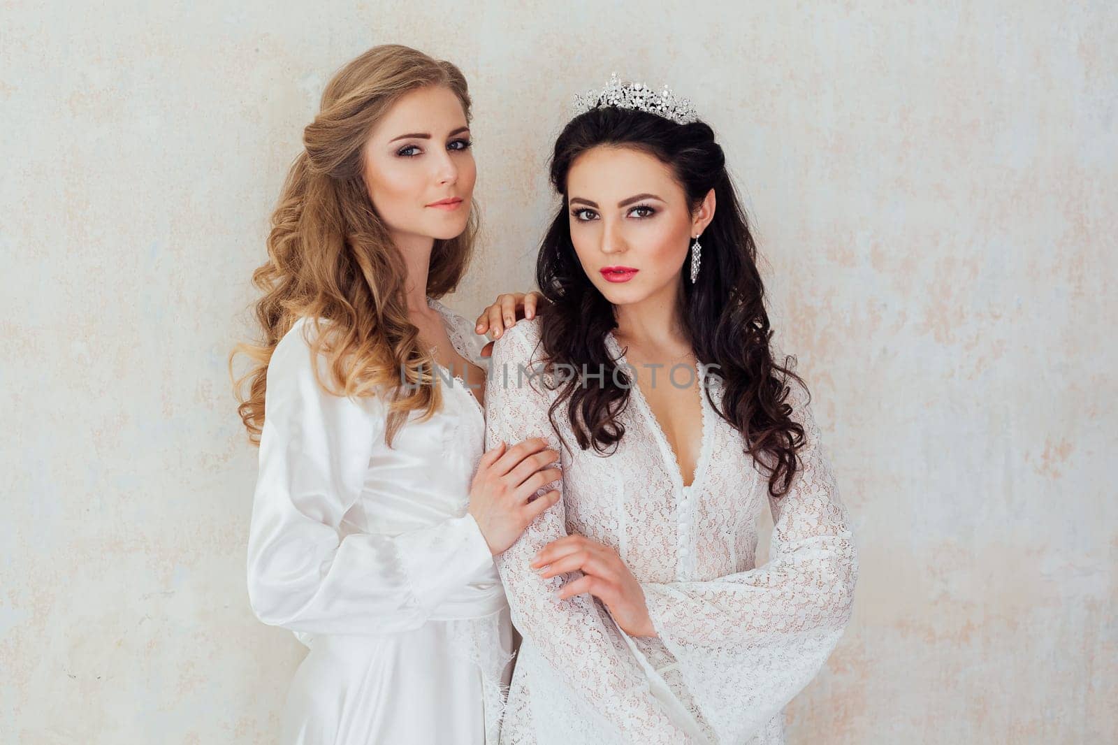 Portrait of two girls in white dresses blonde and bojunetka wedding