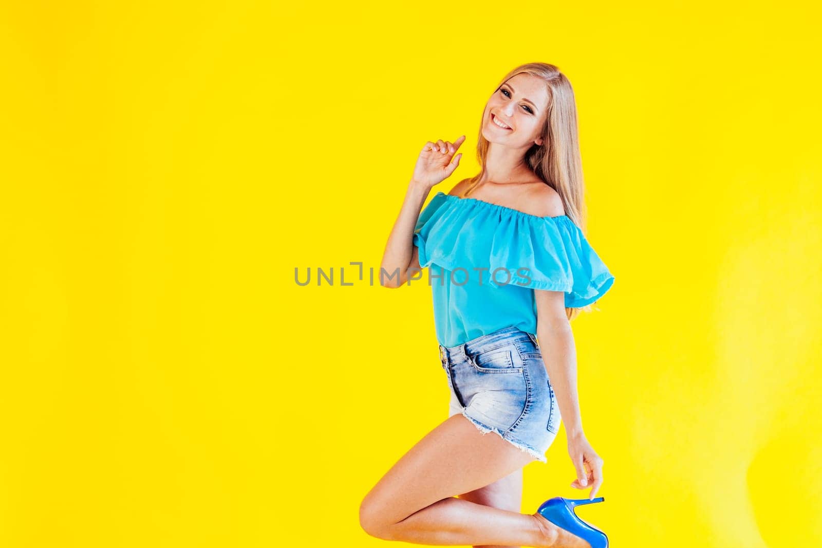 beautiful blonde girl on a yellow background in blue dress 1