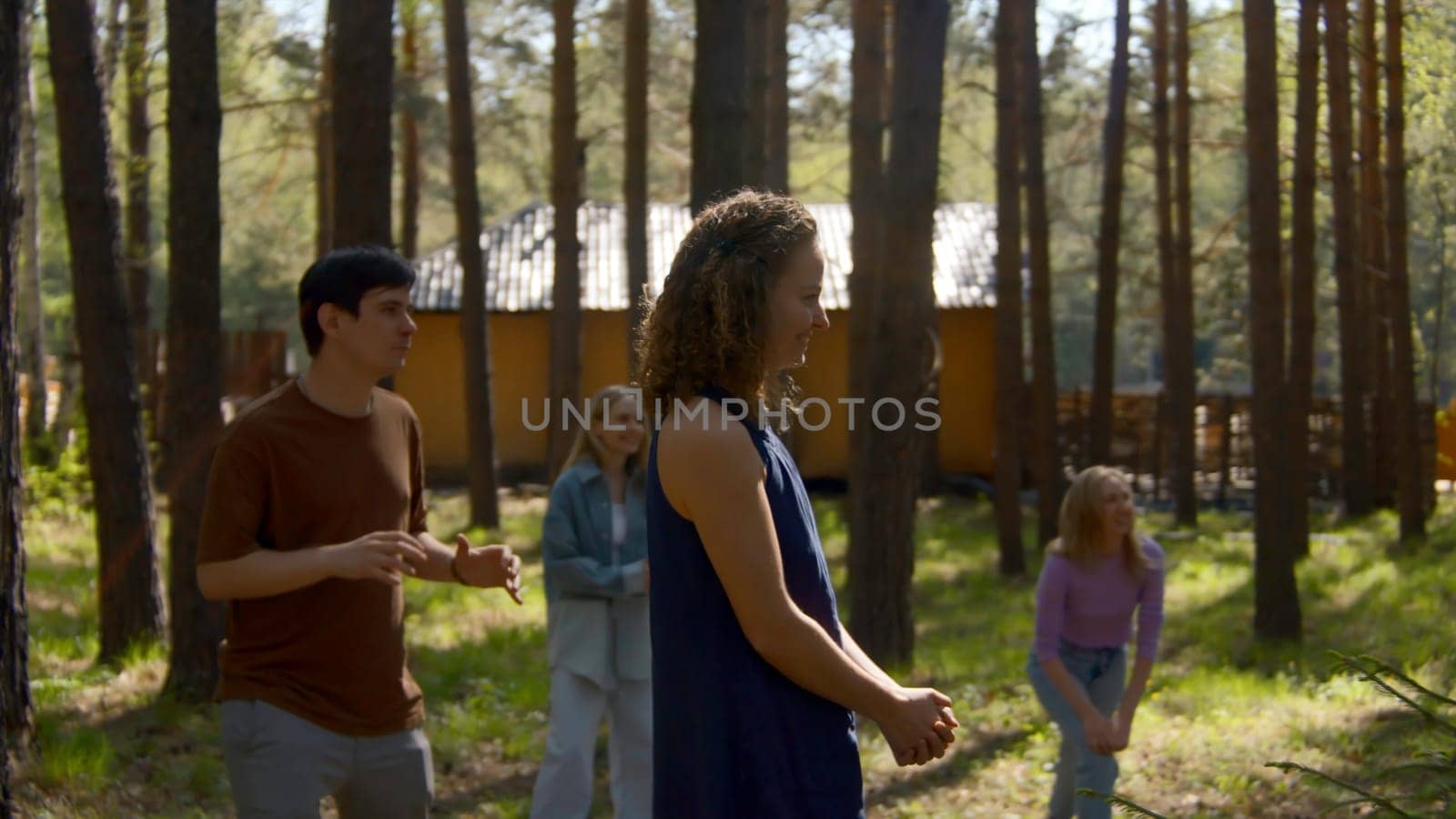People have fun playing volleyball in park. Stock footage. Friends are actively playing volleyball in forest clearing. Fun ball games for group of friends in forest.