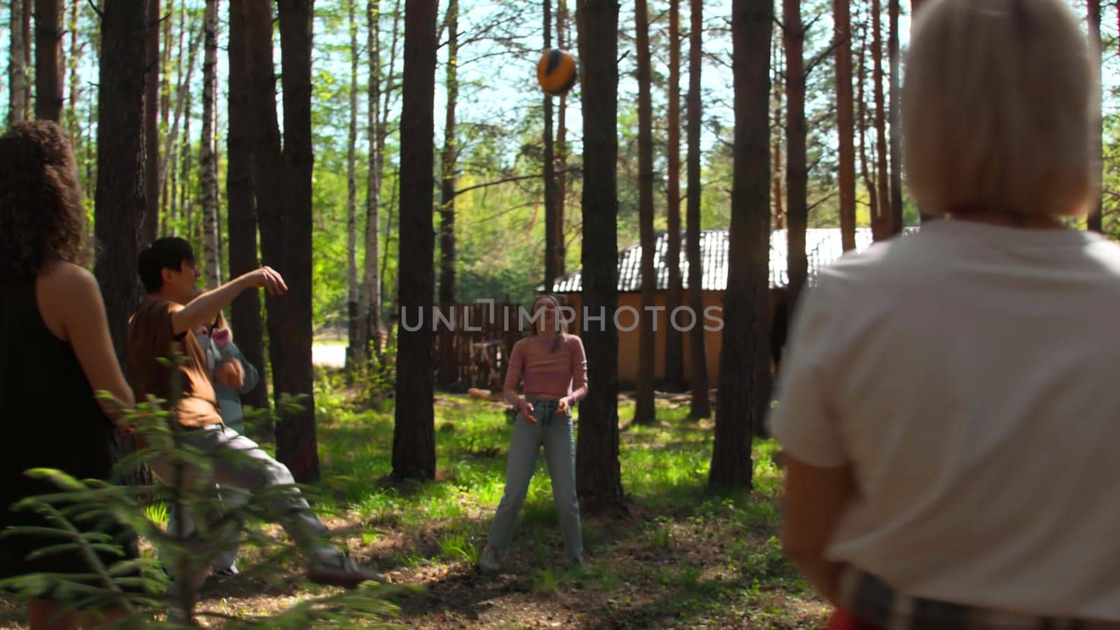 Group of friends is having fun playing volleyball. Stock footage. Friends are playing volleyball in forest clearing. Friends in circle play volleyball in forest on sunny summer day by Mediawhalestock