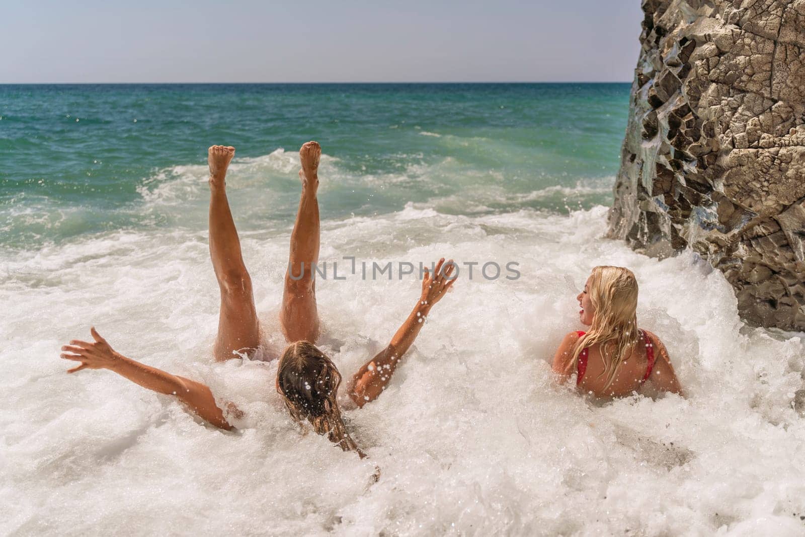 Women ocean play. Seaside, beach daytime, enjoying beach fun. Two women in red swimsuits enjoying themselves in the ocean waves