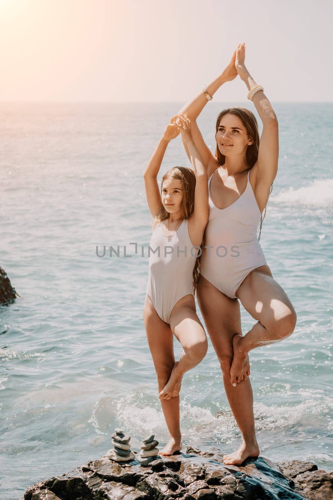 Silhouette mother and daughter doing yoga at beach. Woman on yoga mat in beach meditation, mental health training or mind wellness by ocean, sea