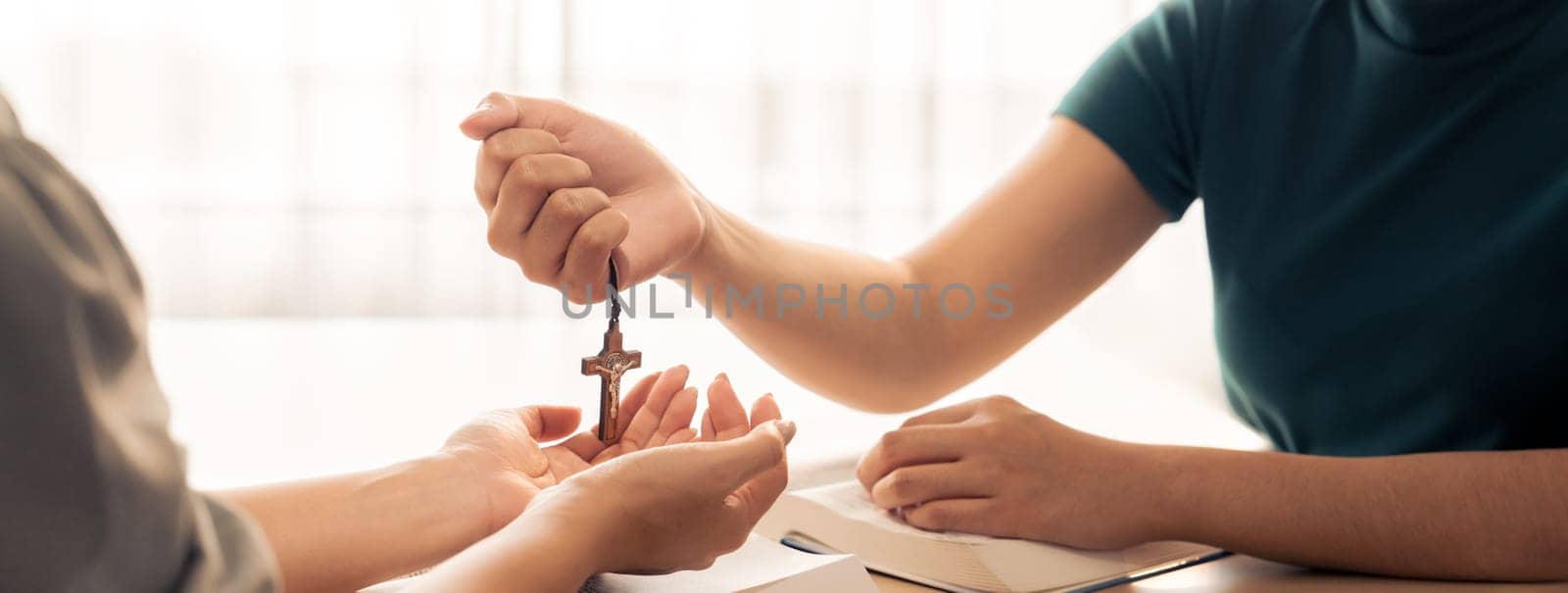 Close-up women prayer deliver holy bible book and holy cross to young believer. Spreading religion symbol. Concept of hope, religion, christianity and god blessing. Warm background. Burgeoning.