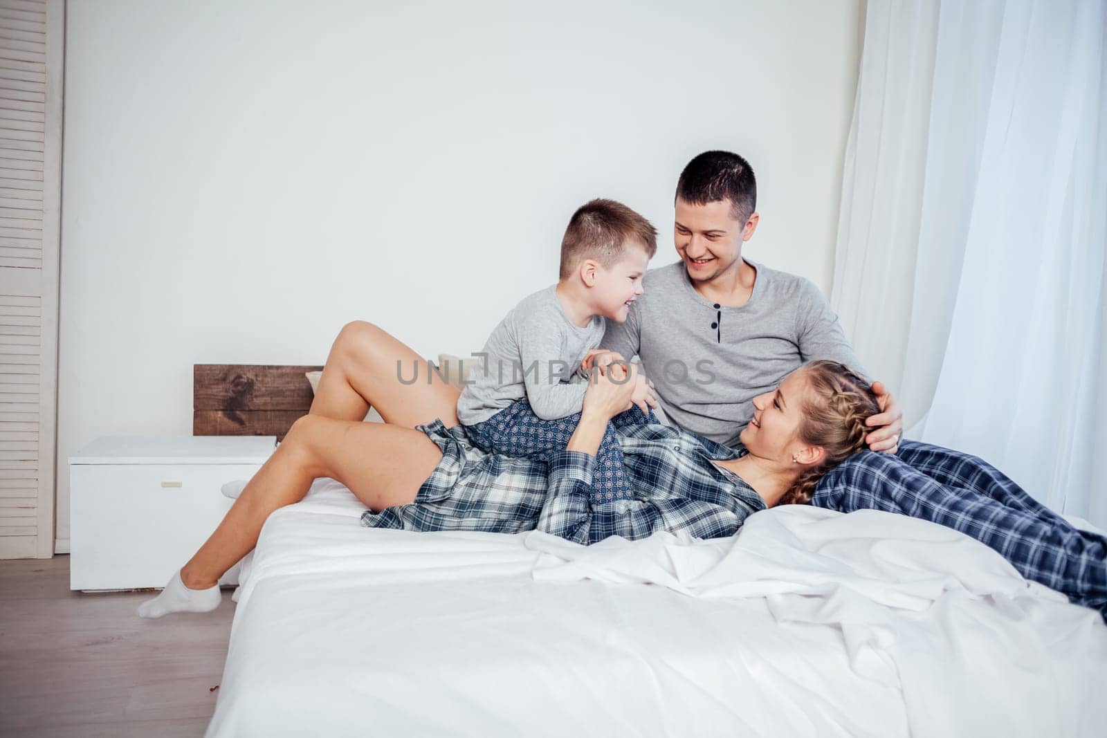 mom dad and son lie on the bed at home woke up