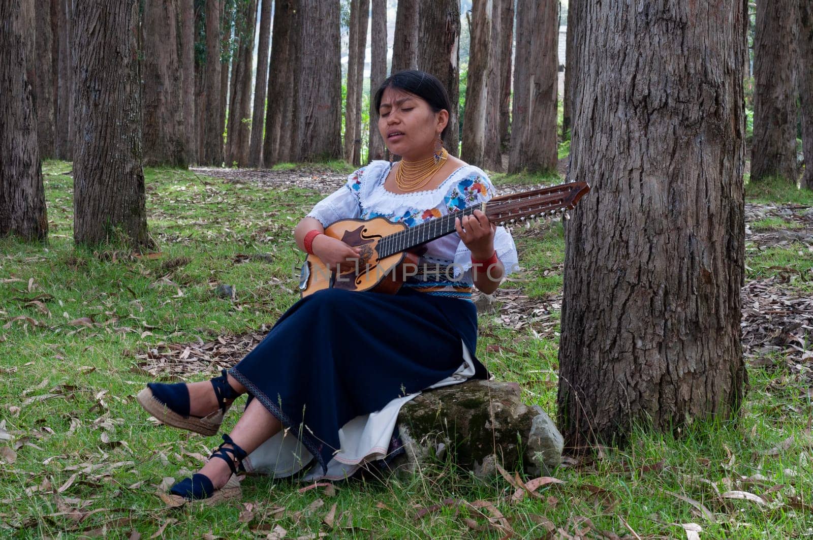 young latin american girl playing a mandolin in the forest while singing with a great feeling on her face. music day by Raulmartin