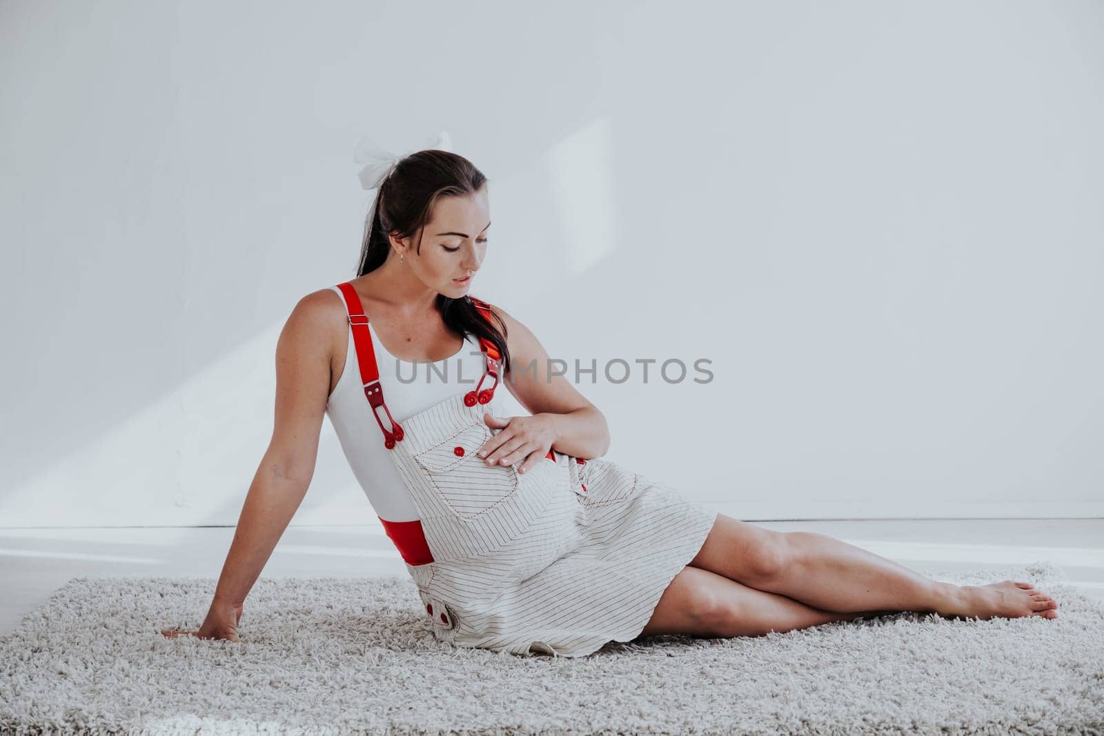 a pregnant woman sitting on the floor talking with a baby in the belly by Simakov