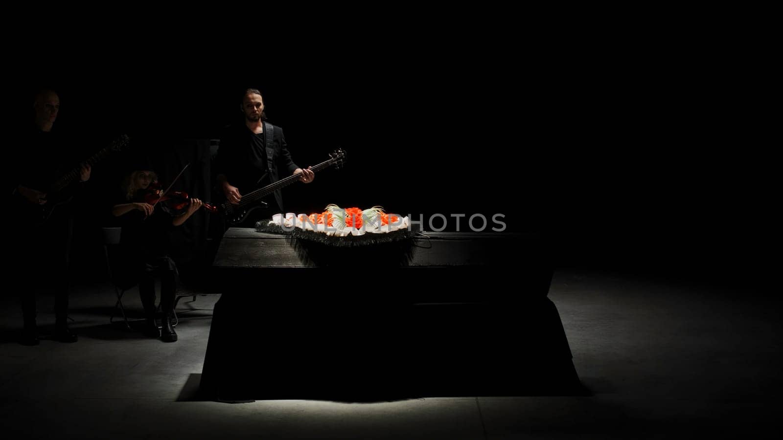 A special ceremony in the hall. Stock footage. A musical group playing music in a dark room next to a chest and flowers. High quality 4k footage