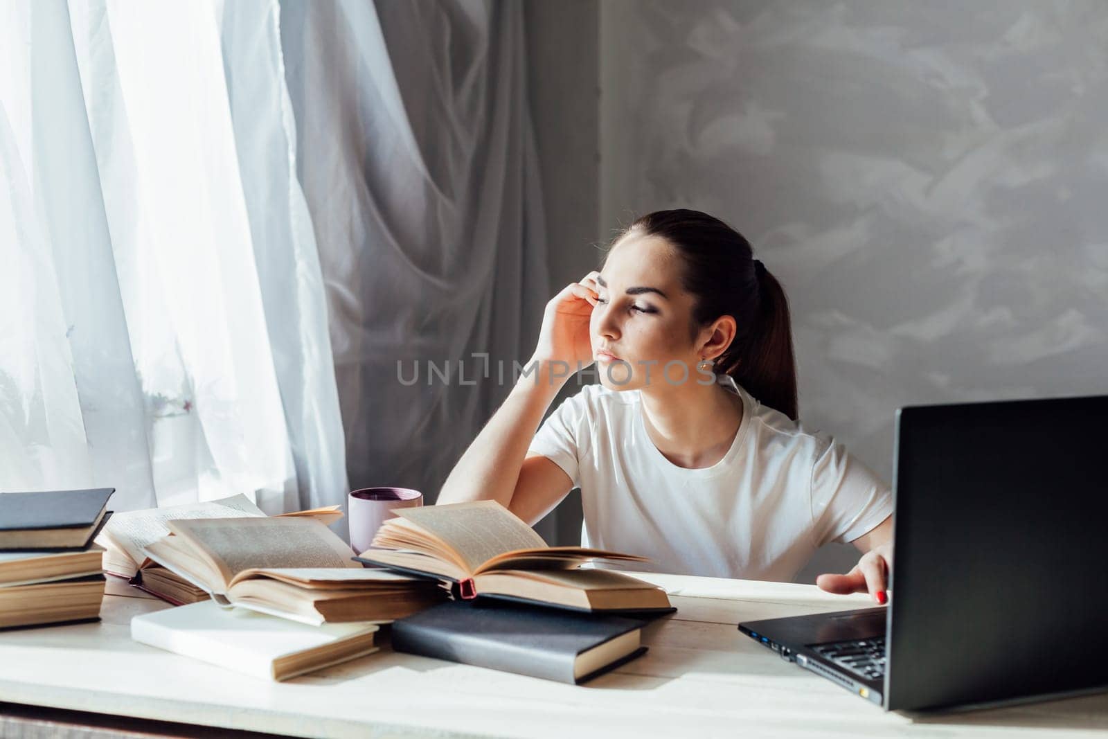 girl reading a book and drinking coffee works at the computer