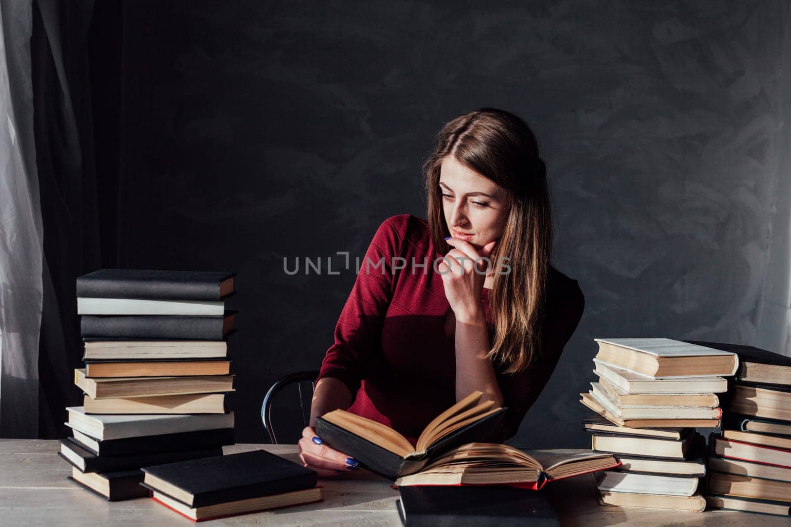the girl sitting at the table reading a lot of books library