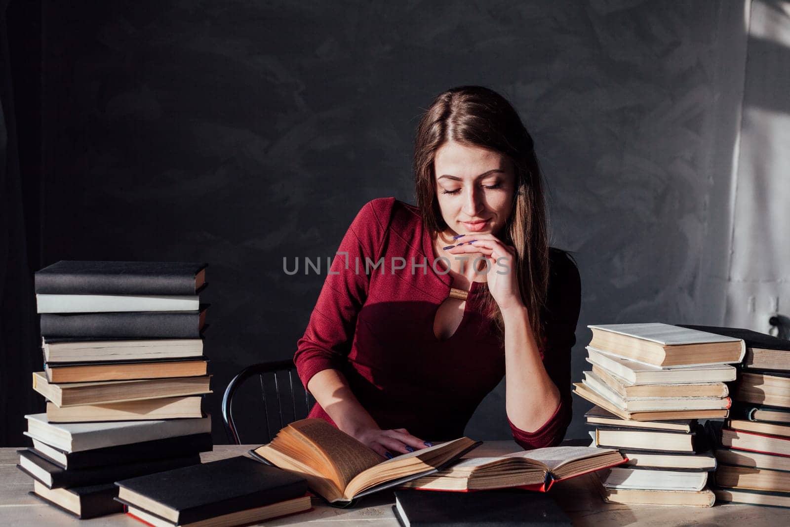 the girl sitting at the table reading a lot of books library