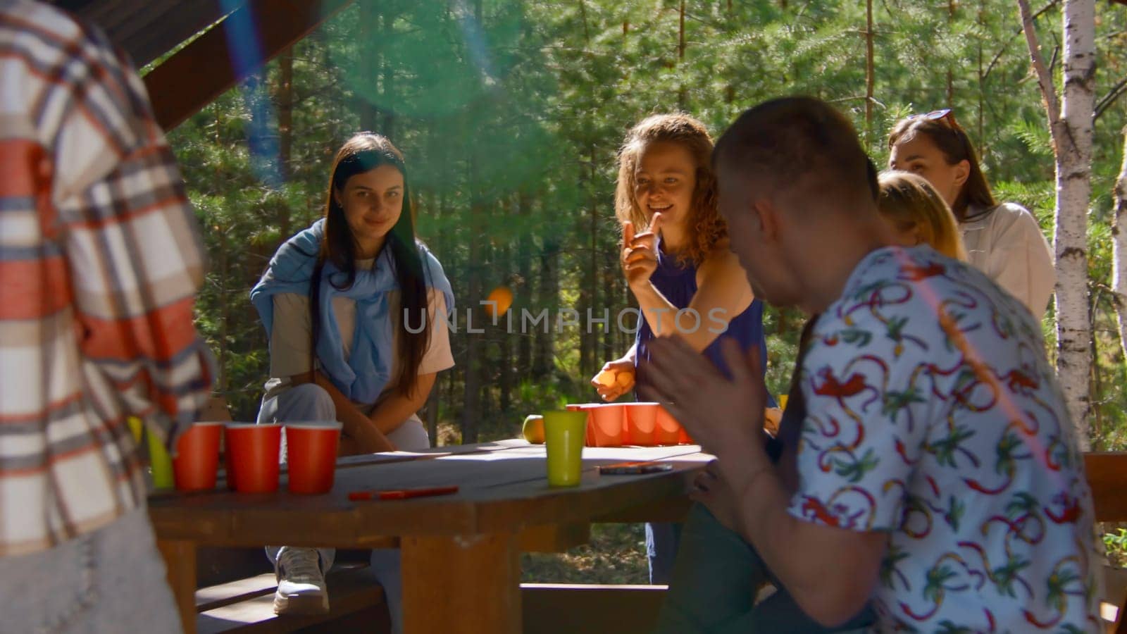 Woman plays beer pong. Stock footage. Beautiful young woman wins at beer pong. Friends rejoice at victory in beer pong in nature in summer.