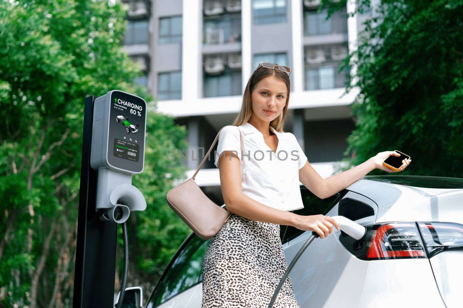 Young woman travel with EV electric car in green sustainable city innards by biancoblue